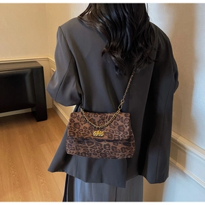 Detail of leopard print crossbody bag with golden chain strap and woven metal turn-lock