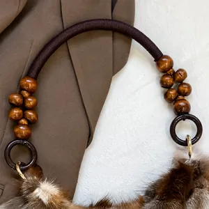 Detailed close-up of woven handle with wooden beads and fox fur on retro shoulder bag