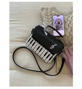 Detail view of piano key pattern with lace trim and treble clef charm on a chic handbag