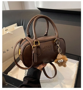 Détail du sac Boston marron avec texte en relief et accessoire ours en peluche en coffret