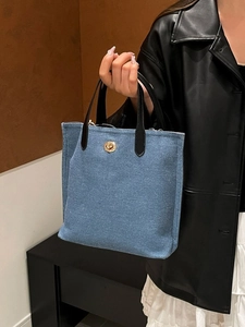 Sac fourre-tout en denim bleu avec poignées en cuir noir et fermoir rotatif doré