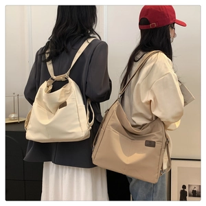 Detail of light beige and khaki nylon backpacks featuring side pockets and leather logo patches