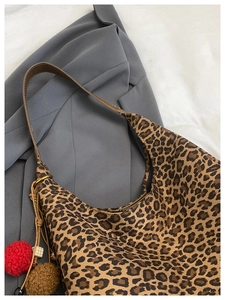 Close-up of leopard print tote bag fabric with plush charms on a gray blazer