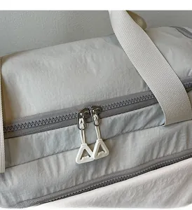 Detail of waterproof nylon travel bag showing dual zippers and durable woven shoulder strap