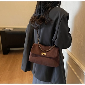 Detail of dark brown suede shoulder bag featuring a vintage gold square twist lock clasp