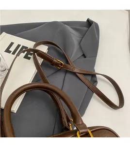 Détails de la bandoulière réglable et des ferrures dorées sur un sac en cuir marron