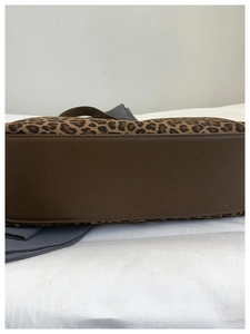 Detail of leopard print tote bag showing brown leather stitching and fabric texture