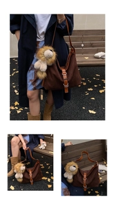 Detail of dark brown canvas tote bag with leather straps and a plush lion charm