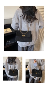 Detail of black suede shoulder bag with gold chain strap and vintage metal lock buckle