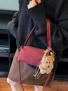 Fashionable burgundy suede hobo bag with plush dog charm for women on shoulder
