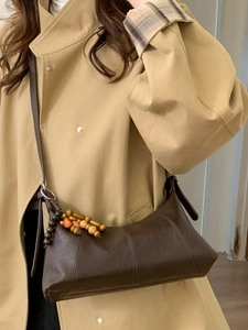 Vintage brown baguette bag with colorful wooden beads on a khaki trench coat