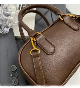 Gros plan sur cuir marron foncé grainé avec quincaillerie dorée et coutures de précision