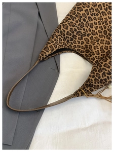 Close-up of leopard print hobo bag showing fabric texture and leather shoulder strap