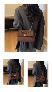 Detail of dark brown suede tote bag with golden metal chain strap and twist-lock clasp
