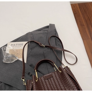 Detail of dark coffee woven bucket bag with gold hardware and stylish long shoulder strap