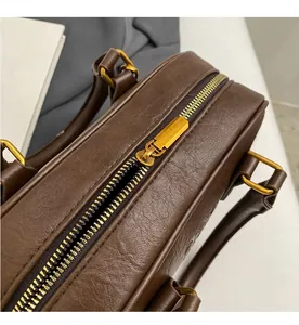 Détail d'une fermeture éclair en métal doré lisse et cuir texturé marron sur un sac