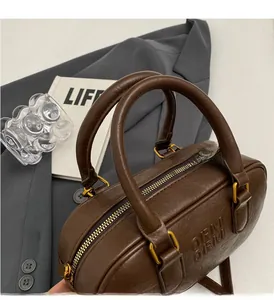 Détail du sac Boston en cuir marron foncé avec lettres ARM ARM gaufrées et métal doré
