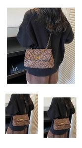 Detail of leopard print tote bag with golden metal turn-lock and chain shoulder strap