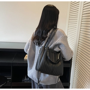 Detail of black woven leather bucket bag featuring a refined V-shaped braided texture