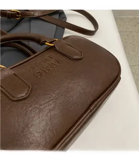 Détail du sac cylindrique en cuir marron foncé avec lettrage ARIM embossé élégant