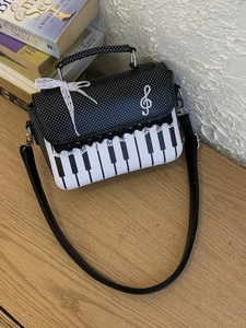 Retro piano themed handbag with musical notes, black and white dots, and shoulder strap