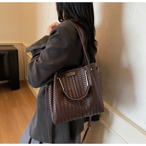 Detail of cross-weave texture on dark brown tote bag with metal handle and strap