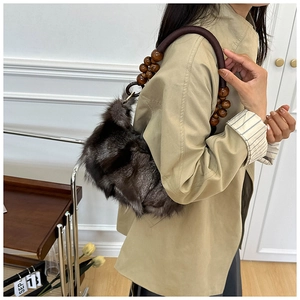 Detail of grey faux fur shoulder bag with brown wooden beaded strap and leather handle
