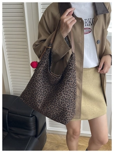Detail of leopard print tote bag with a red pom-pom charm in a stylish indoor setting