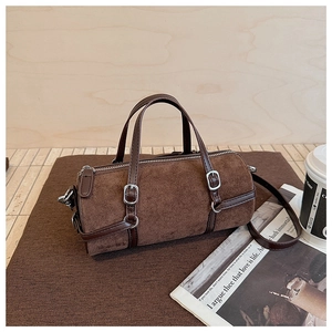 Detailed view of the dark brown cylinder bag showing its soft suede texture and leather strap