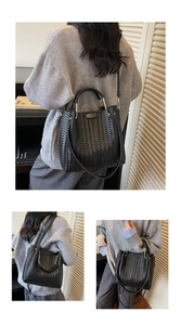 Detailed view of black woven bucket bag with elegant top handle and gold hardware