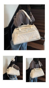 Detail of cream travel bag showing nylon texture, dual handles and adjustable shoulder strap