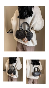 Détail du sac Boston noir vintage avec logo embossé et breloque peluche ours