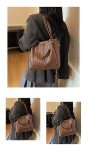 Detail of brown woven tote bag featuring intricate cross-weave texture and metal buckles