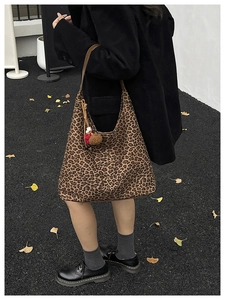 Street view detail of oversized leopard print tote bag with plush ball charm and leather strap