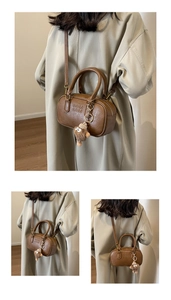 Détail du sac cylindre marron vintage avec embossage ARM ARM et breloque ours