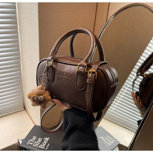 Détail du sac boston marron foncé avec texture cuir grainé et breloque peluche mignonne
