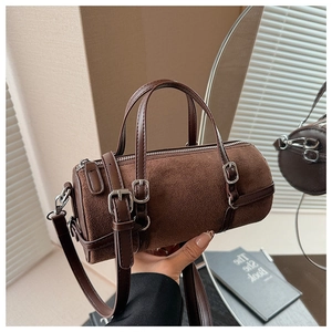 Detail of coffee cylinder handbag showing matte texture and silver buckle accents
