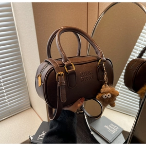 Détail du sac cylindrique en cuir marron avec gaufrage ARM ARM et breloque peluche