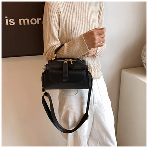Détail du sac à main en cuir grainé noir avec zips dorés et large bandoulière réglable