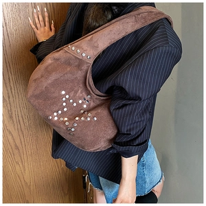 Detalle de bolso de hombro en ante marrón oscuro con diseño de estrella de remaches