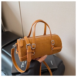 Detail of a brown cylindrical cylinder bag showing suede texture and adjustable straps