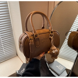 Détail du sac Boston marron avec logo ARM embossé et breloque en peluche
