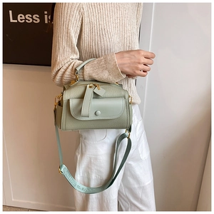 Détail du sac polochon vert clair avec texture grainée et large bandoulière en tissu