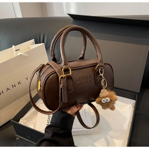 Vue détaillée du sac polochon en cuir marron avec boucle dorée et charm peluche