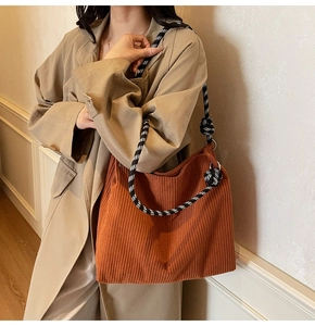 Detail of a large corduroy tote bag in brown with knotted checkered shoulder strap