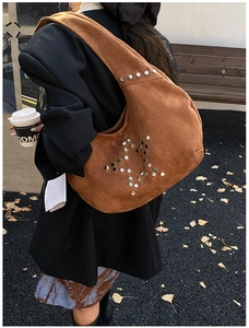 Detail of dark brown suede crescent bag with metal rivet star pattern on model