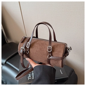 Detail of retro brown cylinder bag featuring silver buckle and suede texture finish