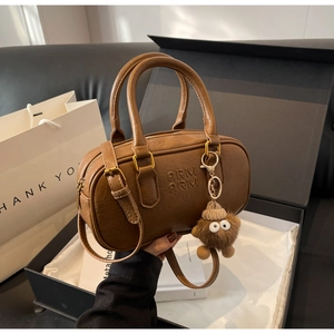 Détail du sac cylindre marron avec gaufrage ARM ARM et pendentif en peluche doux