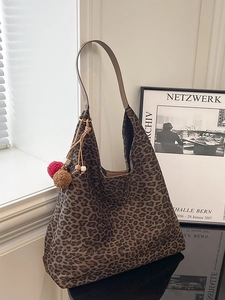 Large leopard print hobo bag with brown shoulder strap and fuzzy tassel charms