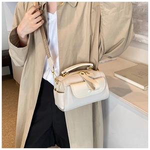 Détail du sac en cuir grainé crème avec ferrures dorées et large bandoulière tissée